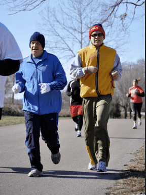two guys dressed for cold weather running down the street